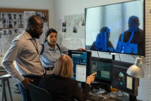 Mature FBI agent showing two young subordinates photo of criminal on screen