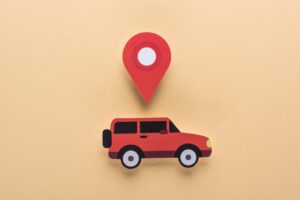 Top view of paper cut car and location mark on beige background