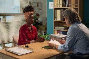 Consulting Middle Aged Black Woman During Social Services Appointment In Office