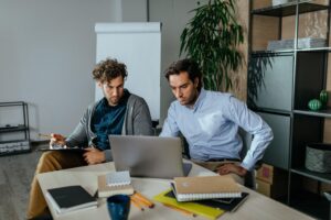 Two male office staff in front of the laptop.